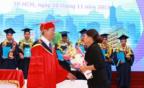 
Bà Trang nhận tấm bằng Kiến trúc sư danh dự từ Hiệu trưởng Đại học Bách khoa. Ảnh: Đại học Bách khoa TP HCM.
