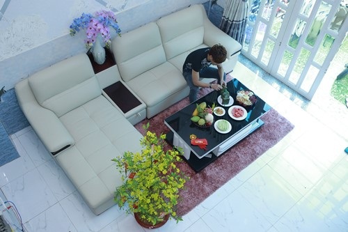 Nội thất phòng khách khá đơn giản với bộ sofa màu trắng kem và thảm màu đỏ nổi bật.