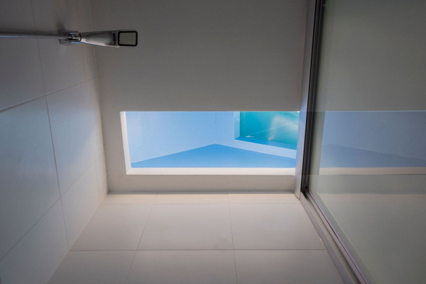 Một phần trần phòng tắm được thay bằng kính chịu lực màu xanh.