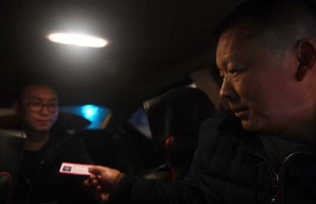 
Anh Wang đưa danh thiếp cho một hành khách sắp xuống xe.
