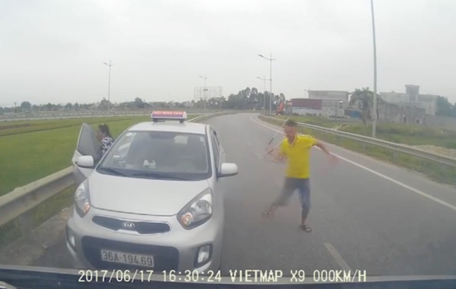 Sau khi xin đường không được, tài xế taxi liền quay lại xe lấy tuýp sắt ra đe dọa (Ảnh cắt từ clip)