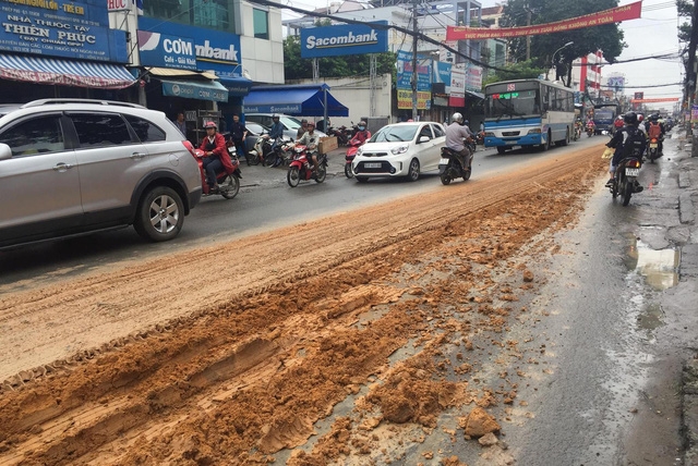 Hàng tấn đất đỏ đổ tràn trên đường Lê Văn Việt, quận 9, TPHCM từ chiếc xe ben không che chắn.