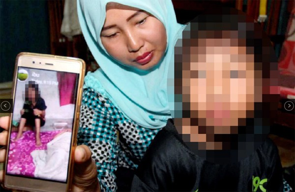 Người mẹ giơ bức ảnh con gái bị bạo hành do chị chồng cũ gửi cho.