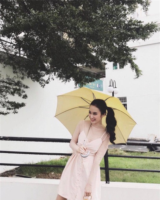 
Angela Phương Trinh gợi ý một trong những cách xuống phố trong ngày mưa gió. Cô nàng khéo lựa chọn một chiếc ô màu vàng nhạt để hòa cùng gam màu hồng pastel dịu dàng của váy áo.
