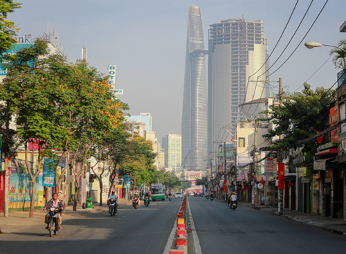 8h, đường Nguyễn Tất Thành (quận 4) hướng về trung tâm thành phố khá thông thoáng (trái). Con đường này ngày thường đông xe từ sáng sớm. Cứ nhìn vào dòng người lũ lụt rời Sài Gòn về quê ăn Tết là đủ hiểu bình thường ở đây đông thế nào, anh Tư (39 tuổi) chờ khách đi xe ôm, cho biết.