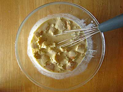 Bánh mì gối cắt bỏ diềm, thái miếng vuông nhỏ, thả vào trong hỗn hợp kem. Dùng phới lồng trộn đều.