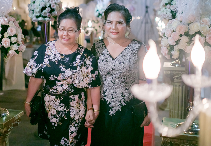 
Mẹ cô dâu (trái) và mẹ chú rể thân thiết nắm tay nhau lên sân khấu làm lễ cùng hai con.
