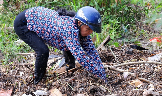Chị Lê Thị Lan bươi các đống rác dưới suối Ông Hường tìm kiếm bé Trường - Ảnh: A LỘC