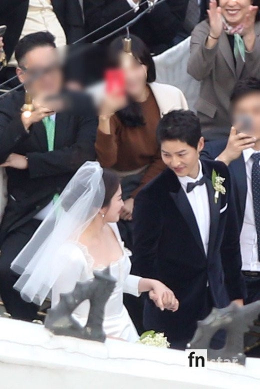 Chú rể nắm chặt tay cô dâu. Trong ngày cưới, Song Joong Ki có nhiều biểu cảm tươi trẻ, giống hệt hình tượng của anh ở Hậu duệ mặt trời.