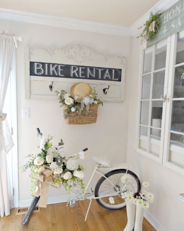 Hiên nhà được đặt chiếc xe đạp của bé sơn màu trắng. Những bông hoa trắng cũng được kết trong giỏ xe và đôi ủng cũ kỹ bên cạnh. Không gian đượm màu vintage, nhẹ nhàng và bình yên với cách trang trí vô cùng đơn giản này.