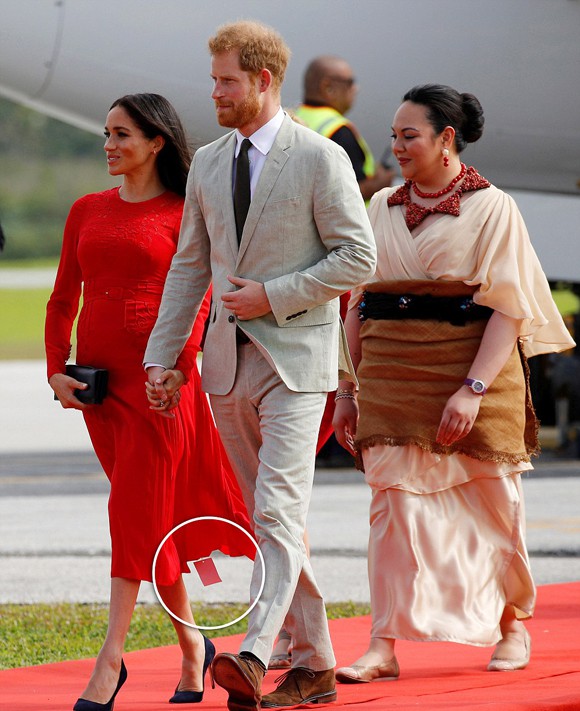 Nữ công tước xứ Sussex để lộ tem mác của chiếc váy Self Portrait 444 USD khi xuống máy bay ở Tonga chiều 25/10. Ảnh: Reuters.