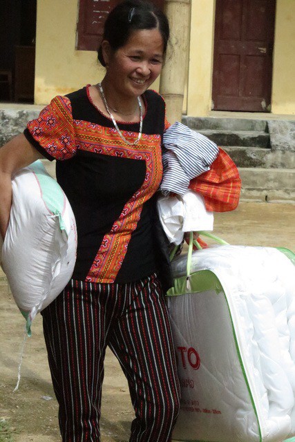 Niềm phấn khởi của bà con khi được tặng những phần quà thiết thực là chăn ấm, gạo và quần áo