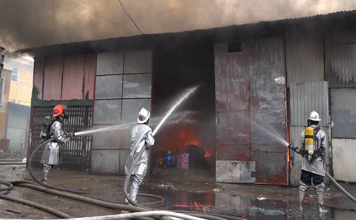 Lính cứu hỏa phun nước dập lửa trong nhà xưởng. Ảnh: H.M