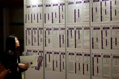 Một phụ nữ đọc thông tin tuyển dụng trong ngày hội việc làm ở Seoul. Ảnh: Reuters