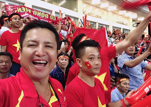 Nghệ sĩ Chí Trung (trái) cổ vũ đội tuyển Việt Nam ở sân vận động quốc gia Mỹ Đình (Hà Nội).