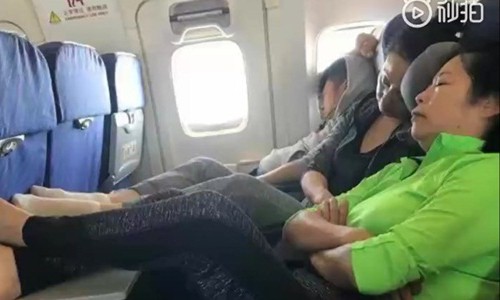Người phụ nữ vừa ngủ vừa gác chân lên bàn ăn trên máy bay. Ảnh cắt từ video.