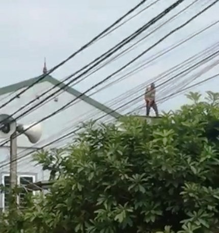 
Đối tượng bế bé trai leo lên mái nhà.
