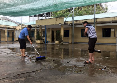 Gi&aacute;o vi&ecirc;n trường THCS An Ph&uacute; Đ&ocirc;ng (quận 12) dọn dẹp s&acirc;n trường khi nước đ&atilde; r&uacute;t. Ảnh: Mạnh T&ugrave;ng.