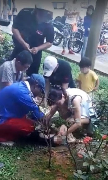 Người d&acirc;n ph&aacute;t hiện cậu b&eacute; nằm tr&ecirc;n b&atilde;i cỏ dưới ch&acirc;n t&ograve;a nh&agrave; ở Sengkang, Singapore s&aacute;ng 25/11. Ảnh: Straits Times.