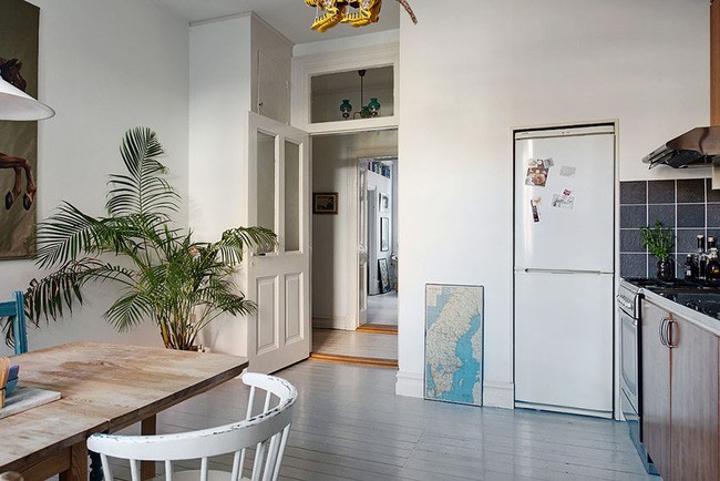 Bên cạnh bàn ăn là khu vực bếp nấu. Đây là nơi được sắp xếp khéo léo và gọn đẹp. Tủ lạnh được đẩy lùi vào sát tường màu trắng giúp không gian bếp khi nhìn vào không có quá nhiều chi tiết phức tạp. Bếp nấu với cánh tủ màu gỗ, nhấn nhá cũng bằng màu ghi đen tiện lợi.