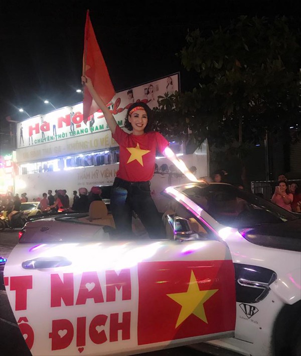 
Hoa hậu Ngọc Diễm đứng l&ecirc;n chiếc &ocirc;t&ocirc; với d&ograve;ng chữ Việt Nam v&ocirc; địch để vẫy cờ ch&uacute;c mừng chiếc cup AFF m&agrave; c&aacute;c cầu thủ vừa đoạt được.
