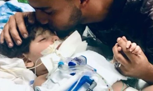 Bố của bé Abdullah hôn con trai trên giường bệnh. Ảnh: CBS.