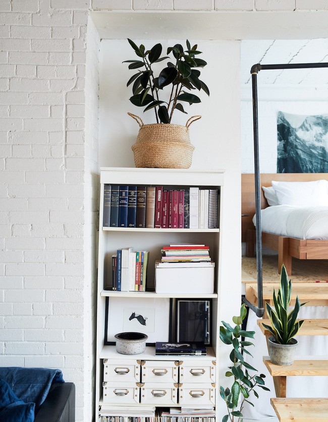 Góc đọc sách với kệ nhỏ xinh xắn đặt bên bậc thang lên phòng ngủ.