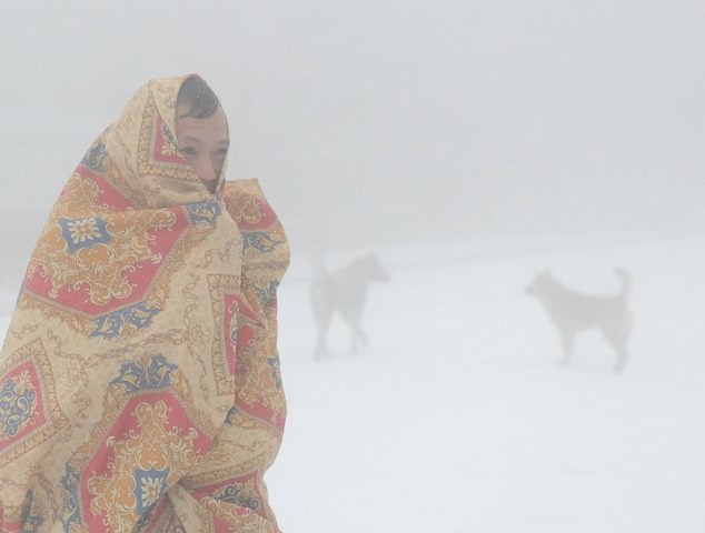 
Một du khách đang trùm chăn đi trong tuyết lạnh do chủ quan không mang nhiều quần áo.
