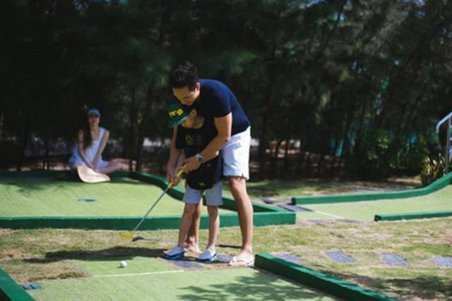 Hà Hồ ngồi trong bóng mát, cô chăm chú nhìn người yêu dạy cách chơi golf cho Subeo.