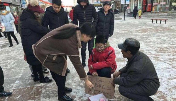 Những người qua đường dừng lại cho Zhang tiền sau khi biết cậu bé đang ăn xin để cứu mẹ. Ảnh: SCMP