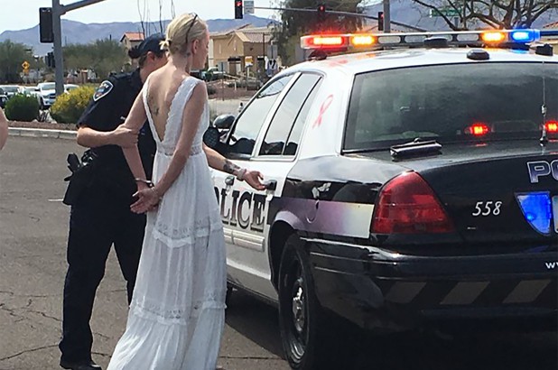 Cô dâu Amber Young, trong bộ váy cưới trắng muốt, đã bị còng tay giải về đồn.