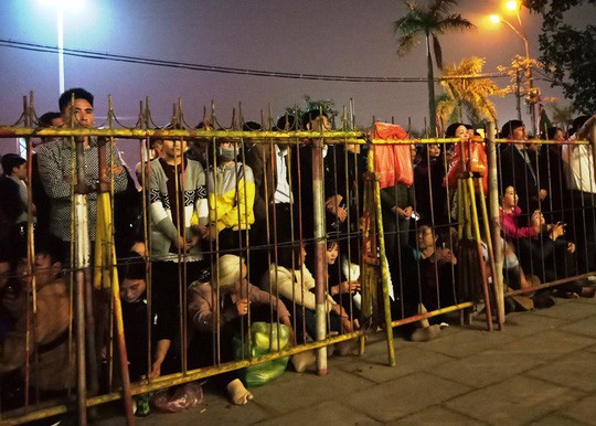Người dân ngồi chờ phía ngoài rào sắt để vào trong đền khi lễ kết thúc.