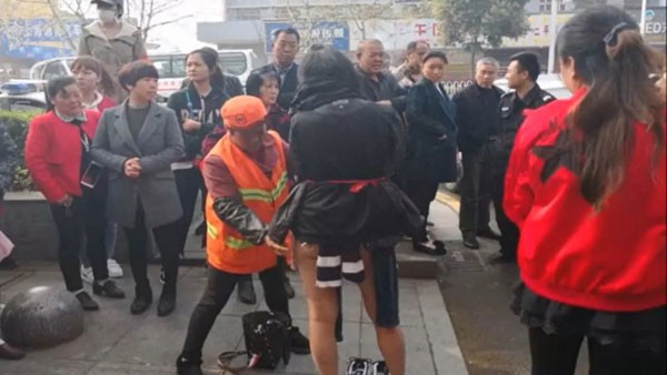 Nữ đạo chích được khoác tạm quần áo che người trước khi bị giải đi.