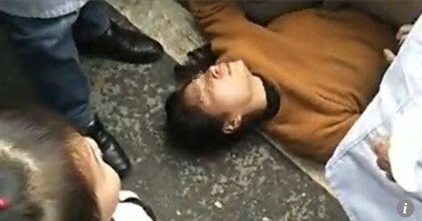 Người vợ giả vờ động kinh, nằm ngay dưới xe cảnh sát để chồng được thả ra. Ảnh: SCMP