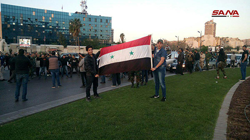 Người dân cầm quốc kỳ Syria ủng hộ chính quyền ở quảng trường Umayyi, Damascus. Ảnh: SANA