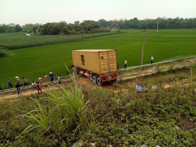 
Sau khi đ&acirc;m v&agrave;o đu&ocirc;i xe biển xanh, xe conainer t&ocirc;ng lan can lao xuống ruộng.
