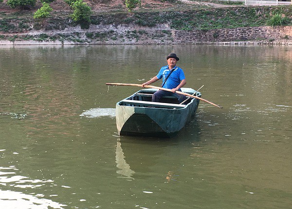 ông Xinh chèo thuyền ra giữa ao để cho đàn cá, bảo đảm cho đàn cá phát triển khỏe mạnh.