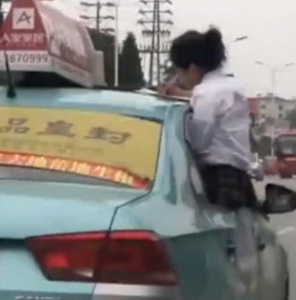 Nữ sinh cắm cúi làm bài tập, mặc cho chiếc xe đang phóng trên đường phố đông đúc. Ảnh cắt từ video.