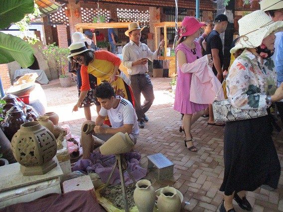 Du khách thích thú với việc nặn đất sét tạo ra nhiều sản phẩm ở làng gốm Thanh Hà.