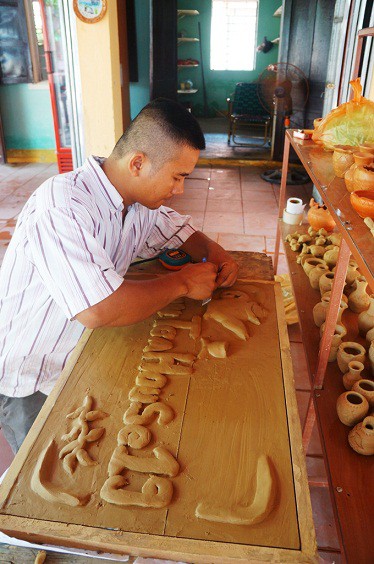 
Một thợ ở làng gốm đang tạo một bức tranh với hoa văn sắc sảo từ đất sét.
