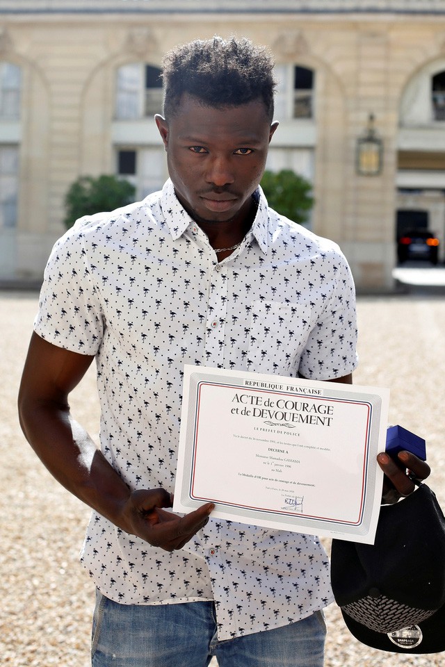 Mamoudou Gassama khoe bằng khen về hành vi dũng cảm được Tổng thống Pháp Emmanuel Macron trao tặng sau buổi tiếp tại Điện Elysée sáng 28-5 - Ảnh: REUTERS