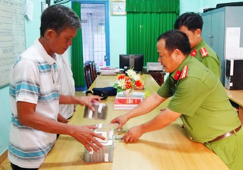 
Cảnh sát trao tiền thu hồi cho ông Ba. Ảnh: Báo Long An.
