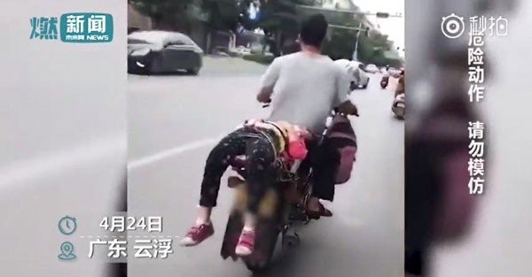 Người bố treo bal&ocirc; của con g&aacute;i trước xe v&agrave; tr&oacute;i con đằng sau để chở đến trường. Ảnh cắt từ video.