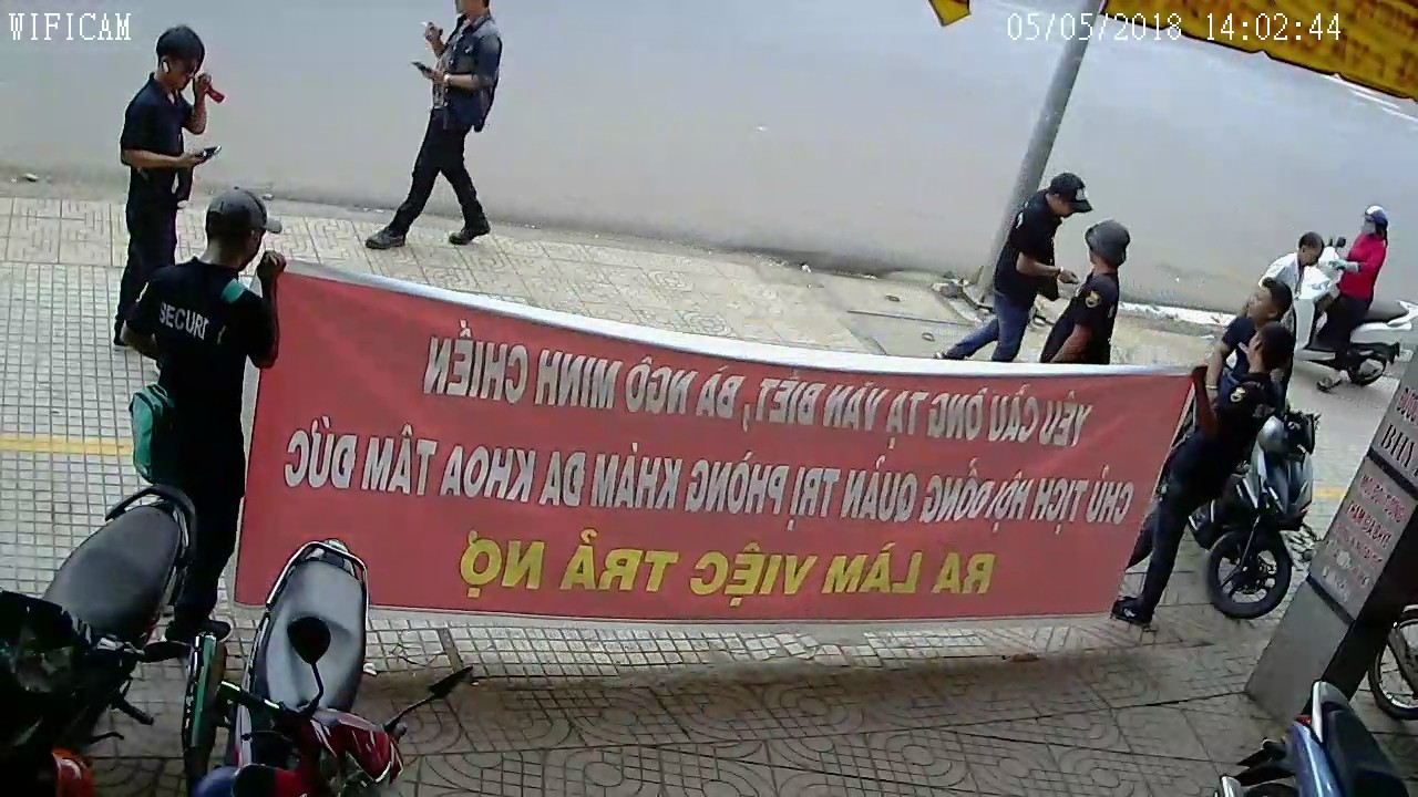 Nhóm người xăm trổ liên tục hò hét, căng băng rôn nhiều ngày trước cửa phòng khám. Ảnh: Cắt từ video.