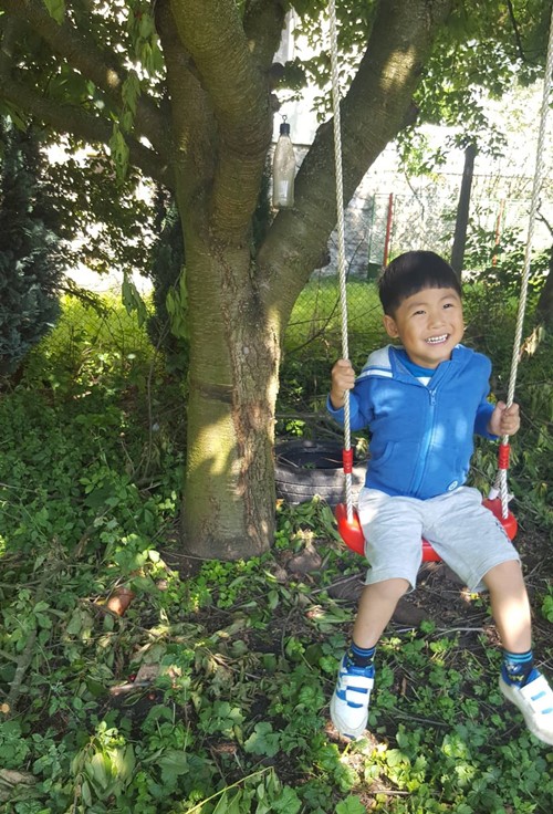 Cậu con trai 5 tuổi của chị Thủy nô đùa dưới bóng mát cây ăn trái trong vườn mẹ.