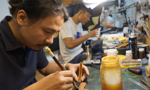 Anh Cao Duy Long (tr&aacute;i) v&agrave; cộng sự duy nhất cặm cụi l&agrave;m d&acirc;y đồng hồ da trong căn xưởng nhỏ x&iacute;u của m&igrave;nh ở phố Li&ecirc;n Tr&igrave; (Ho&agrave;n Kiếm, H&agrave; Nội).  Ảnh: Trọng Nghĩa.