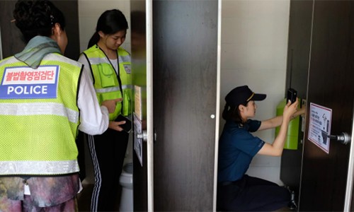 Cảnh sát và tình nguyện viên rà soát các camera quay lén tại một nhà vệ sinh ở bể bơi công cộng thành phố Changwon hôm 23/7. Ảnh: Washington Post