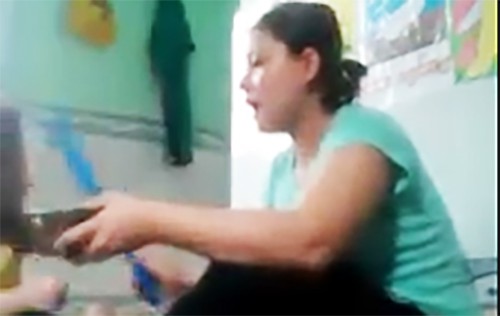 Bảo mẫu cầm c&acirc;y nhựa đ&aacute;nh b&eacute; g&aacute;i khi cho ăn. Ảnh: Cắt từ clip.