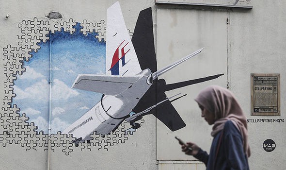 Một phụ nữ đứng gần bức tranh về MH370.