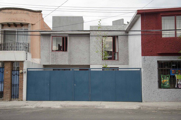 Mặt tiền của ngôi nhà gây ấn tượng với cánh cổng xanh cổ vịt và màu tường đỏ - xám.